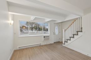 Toms River triplex for rent - A spacious room with a staircase and a window overlooking a street.