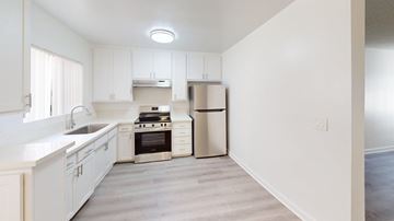 Granada Hills apartment for rent - A kitchen with white cabinets and a stainless steel trash can.