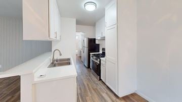 Granada Hills apartment for rent - A modern kitchen with white cabinets and a wooden floor.