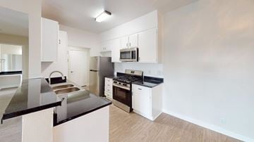 Northridge apartment for rent - A kitchen with white cabinets and black countertops.