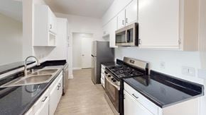 Northridge apartment for rent - A kitchen with white cabinets and black countertops.