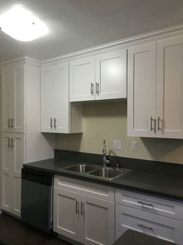 Van Nuys apartment for rent - A kitchen with white cabinets and a black countertop.