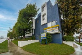 Van Nuys apartment for rent - a blue building with a yellow and white sign in front of it