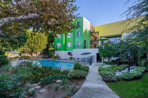 Inglewood apartment for rent - A green and yellow building with a pool in the backyard.