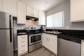 Ventura apartment for rent - A modern kitchen with white cabinets and black countertops.