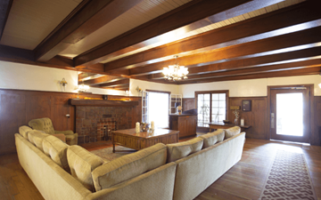 Hollywood apartment for rent - A large beige couch sits in a spacious living room with wooden floors and a fireplace.