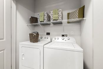 A white washer and dryer in a laundry room with a shelf above it