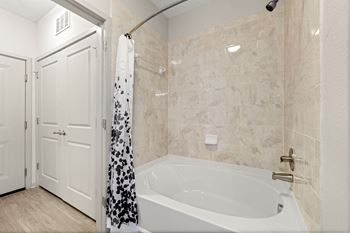 A bathroom with a tub and a shower and a door