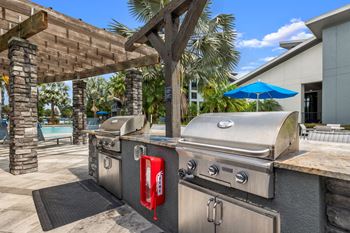 A backyard with two stainless steel barbecue grills and a picnic table