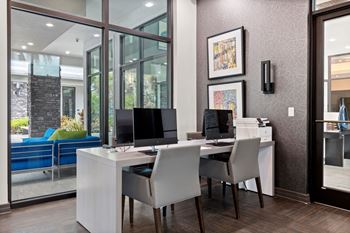 A home office with two computers and a printer on a desk