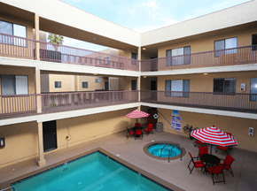 Van Nuys apartment for rent - a balcony with a pool and tables with umbrellas