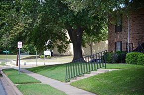 Sherman apartment for rent - a wrought iron fence in front of a tree at Archer Village Apartments,Sherman, Texas, 75092