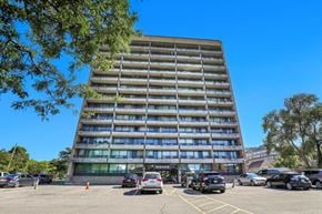 Ottawa apartment for rent - A tall building with a parking lot in front of it.