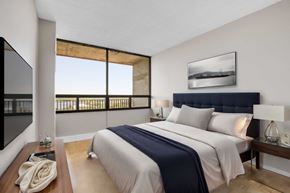Ottawa apartment for rent - A bedroom with a large bed and a balcony with a view.