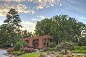 Atlanta apartment for rent - A building with the word "AVILA" on it is surrounded by trees and flowers.