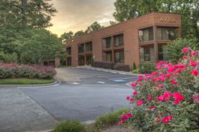 Atlanta apartment for rent - A building with the name AVILA on it is surrounded by flowers and trees.