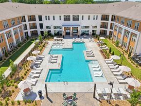 Lagrange apartment for rent - A large swimming pool surrounded by lounge chairs and umbrellas in a courtyard.