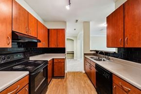 Stonecrest apartment for rent - A kitchen with wooden cabinets and black appliances.