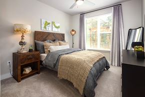Atlanta apartment for rent - A spacious bedroom with a bed, nightstand, and window.