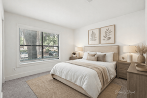 Lithia Springs apartment for rent - A bedroom with a large bed, a window with blinds, and a wall-mounted light fixture.