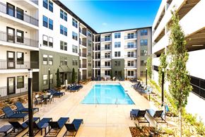 Atlanta apartment for rent - A swimming pool surrounded by lounge chairs and trees in front of apartment buildings.