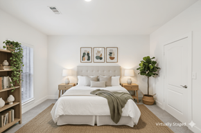 Stonecrest apartment for rent - A bedroom with a large bed, a nightstand with lamps, a plant, and pictures on the wall.