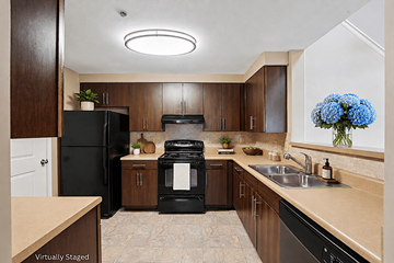 Newnan apartment for rent - A kitchen with black appliances and wooden cabinets.