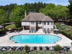 Lawrenceville apartment for rent - a large pool in front of a house with chairs around it