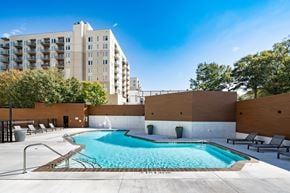 Atlanta apartment for rent - A large swimming pool with lounge chairs and a fence around it.