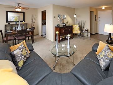 Euclid apartment for rent - A living room with a black leather couch and a glass coffee table.