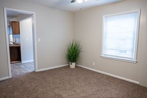 Rapids townhouse for rent - A room with a carpeted floor, a window with blinds, and a plant in a white pot.