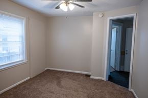 Rapids townhouse for rent - A room with a carpeted floor, a ceiling fan, and a door leading to another room.