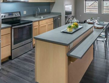 Grand Rapids apartment for rent - A modern kitchen with a stove, oven, and a dining table set for two.
