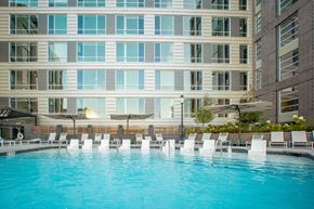 Raleigh apartment for rent - a swimming pool with white chairs in front of a building
