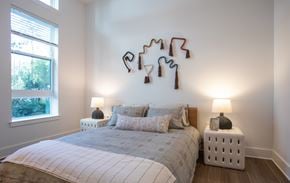 Raleigh apartment for rent - A bedroom with a bed, two lamps, and a wall decoration.