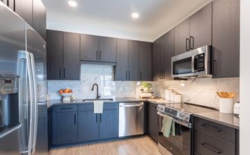 Raleigh apartment for rent - A modern kitchen with dark wood cabinets and stainless steel appliances.