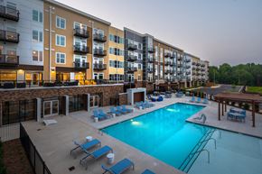 Pittsboro apartment for rent - an outdoor swimming pool with chaise lounge chairs and a fire pit in front of an apartment