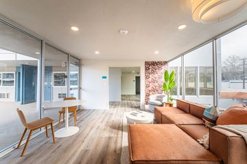 Oakland apartment for rent - A modern living room with a brown leather couch and wooden chairs.