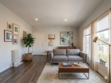 Oakland apartment for rent - A living room with a grey couch, a wooden coffee table, and a painting on the wall.