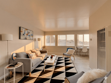 Oakland apartment for rent - A living room with a black and white checkered rug, a grey couch, a white chair, and a painting on the wall.