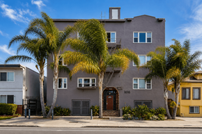 Oakland apartment for rent - A grey house with a brown door and windows surrounded by trees.
