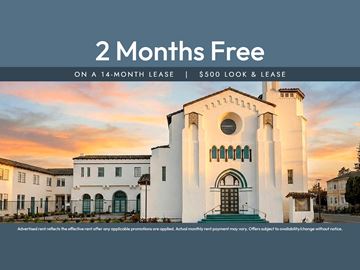 Oakland apartment for rent - A white building with a large arched doorway and a sign offering 2 months free on a 14-month lease.