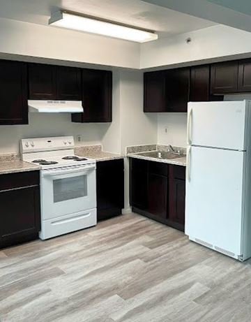 Freehold apartment for rent - A white refrigerator stands in a kitchen with dark brown cabinets.