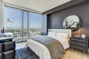 Oakland apartment for rent - A modern bedroom with a large bed and a view of the city.
