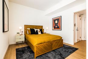 Oakland apartment for rent - One Bedroom Luxury Apartments in Downtown Oakland CA - Alice House - Furnished Bedroom with a Wooden Bed, Hardwood Style Flooring, Rug, Two Cream Nightstands with Drawers and Lamps, and White Walls