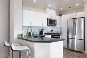 Oakland apartment for rent - Kitchen with stainless steel appliances and bar seating at Aqua Via Apartments, Oakland, CA
