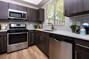 Las Vegas apartment for rent - Spring Valley, NV, 89147 Apartments - Alicante - Kitchen with Hardwood-Style Floor, Quartz Countertops, Stainless-Steel Appliances, and Wooden Cabinets