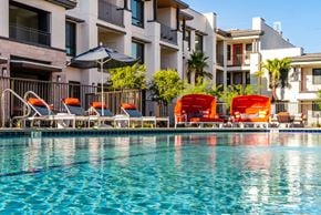 Palm Desert apartment for rent - A pool with chairs and umbrellas in front of a building.