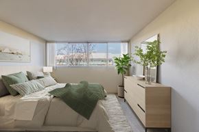 Redwood City apartment for rent - 1-Bedroom Apartments in Redwood City, CA - Avenue Two - Bedroom with Carpet Flooring, Full-Size Bed, Nightstand with Lamp, Dresser, Houseplants, and Large Window at Avenue Two Apartments, Redwood City