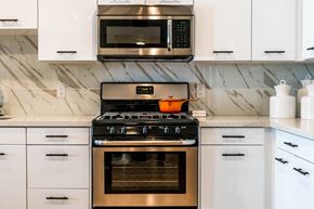 Costa Mesa apartment for rent - A modern kitchen with a stove top oven and microwave above it. at Baker Block, Costa Mesa, CA, 92626
